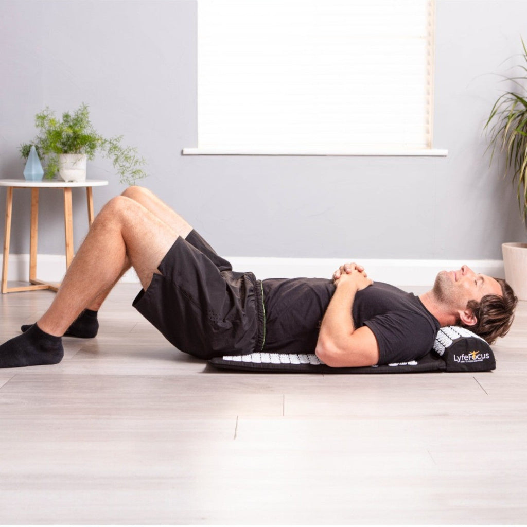 Man exercising on a mat with a pillow under his head in a home setting