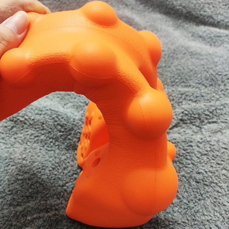 Orange textured object held by a hand on a gray surface