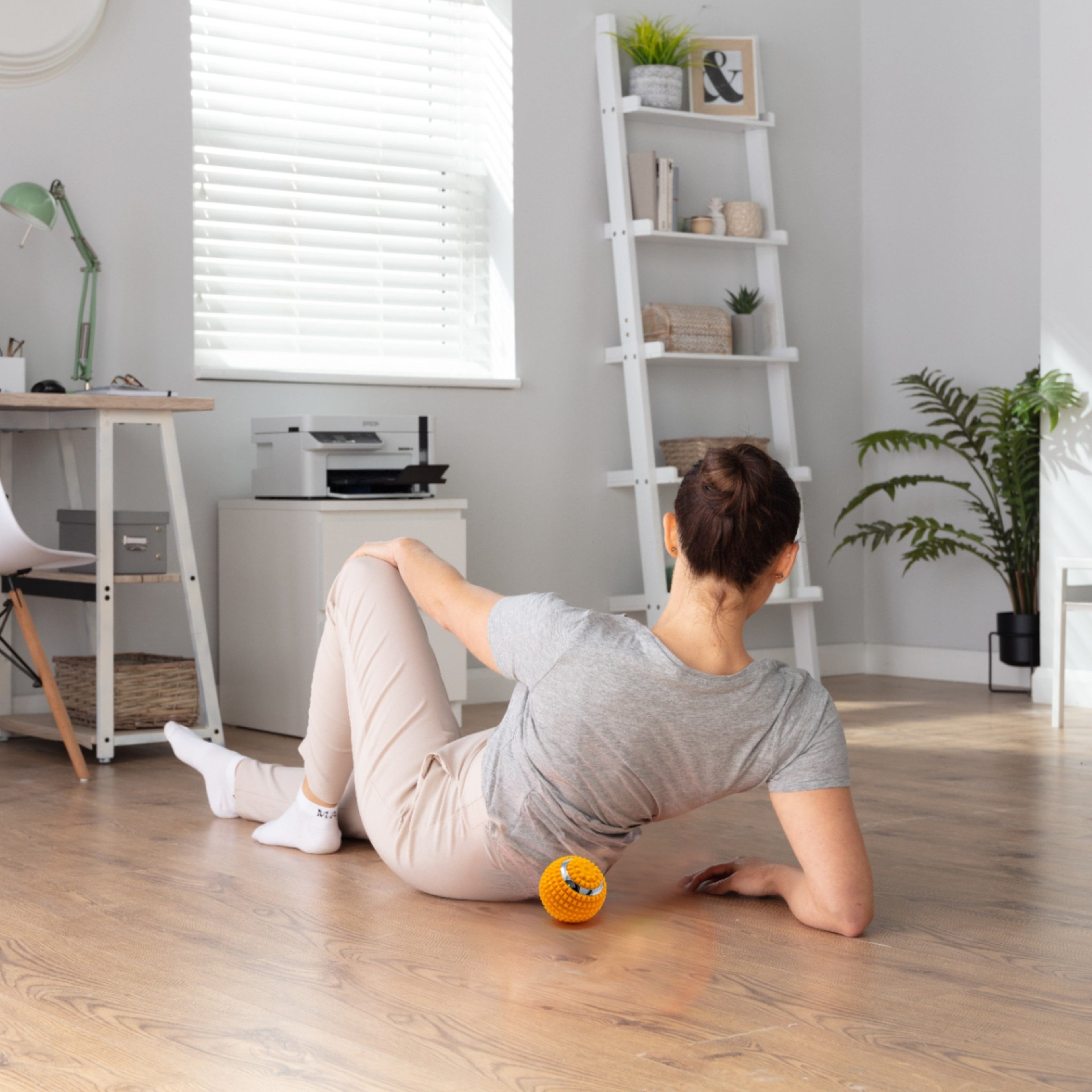 Woman exercising with a ball on a wooden floor in a home office setting