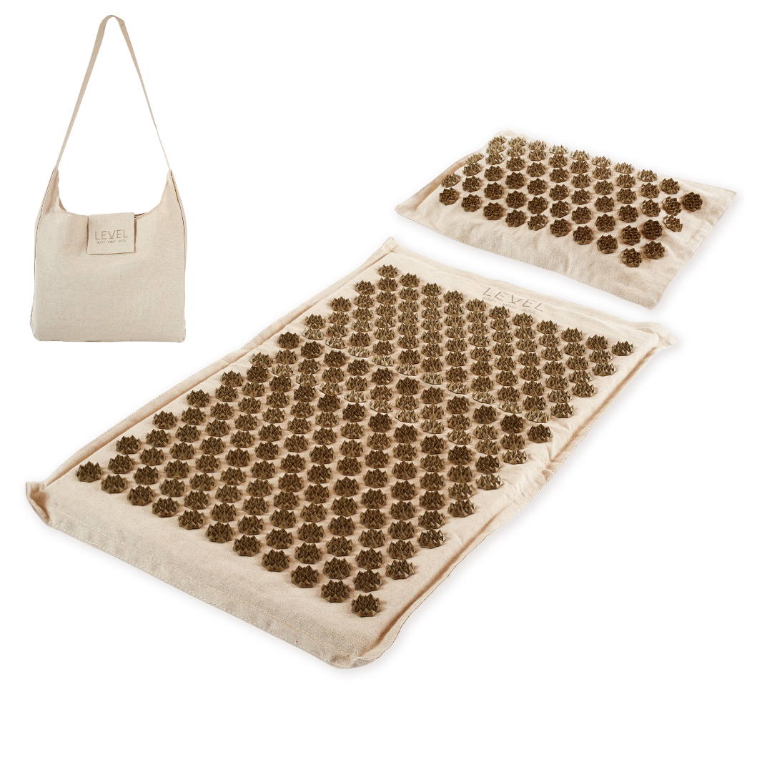 Acupressure mat and pillow set with a beige bag on a white background